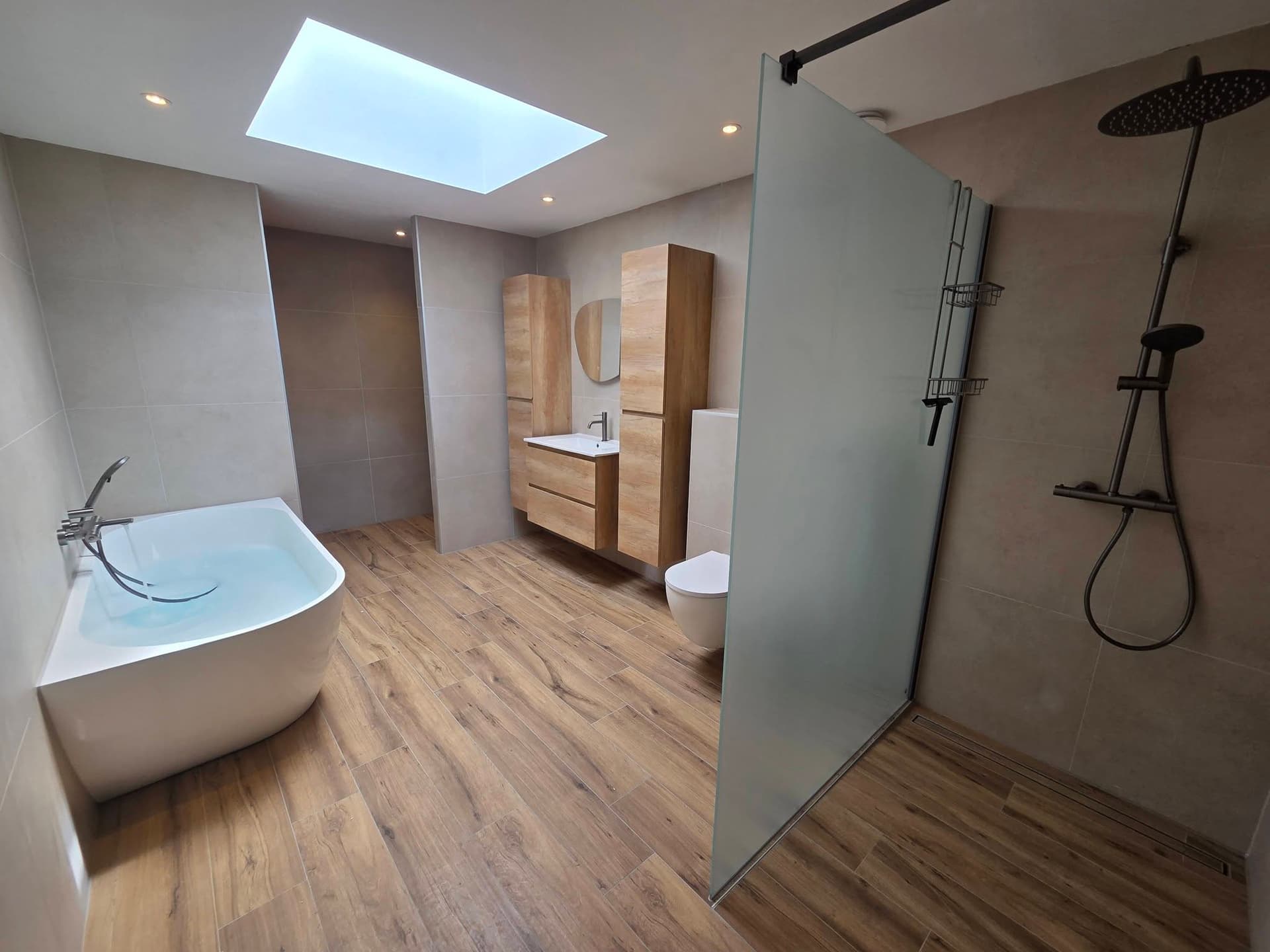 Badkamer met dakraam, vrijstaand bad en houtlook vloer