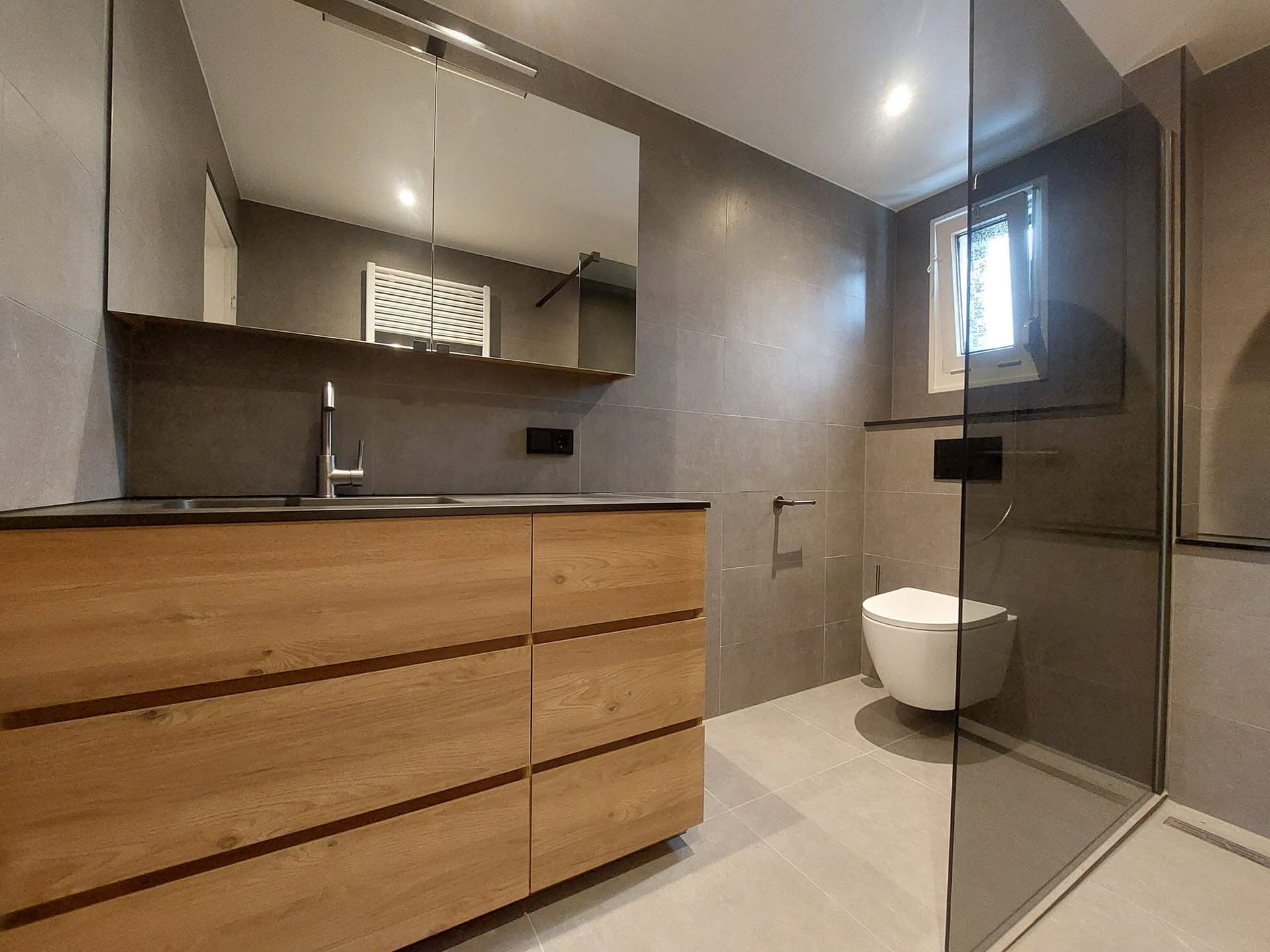 Badkamer met breed eiken wastafelmeubel en spiegelkast
